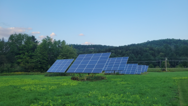 Solar panels on green field with blue sky