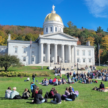 State house in fall with people on lawn